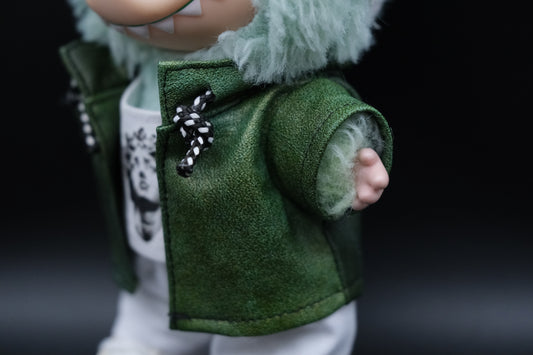 close up of  Labubu's green leather jacket, white t-shirt, and white pants